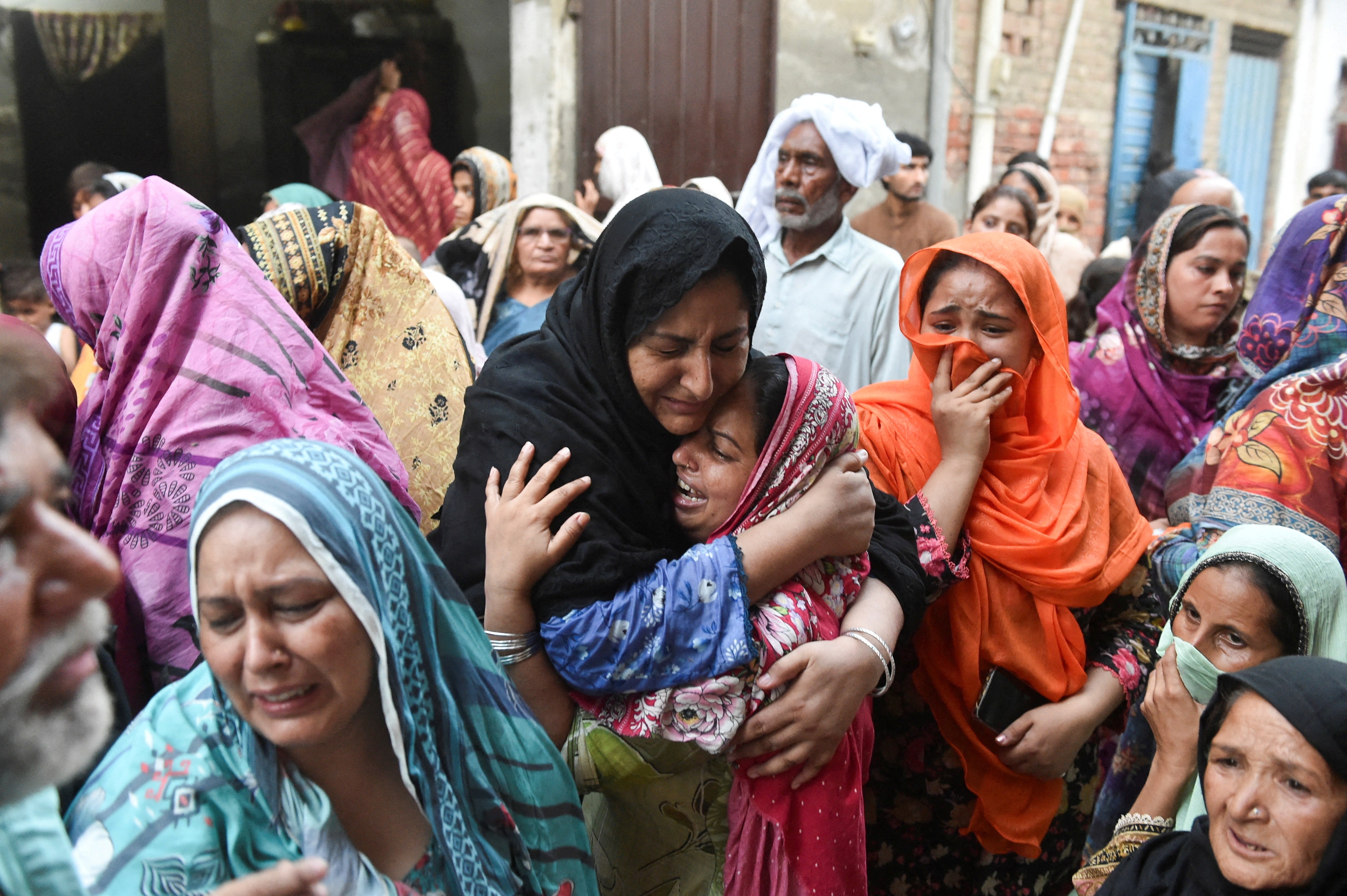 women embrace and cry, surrounded by people