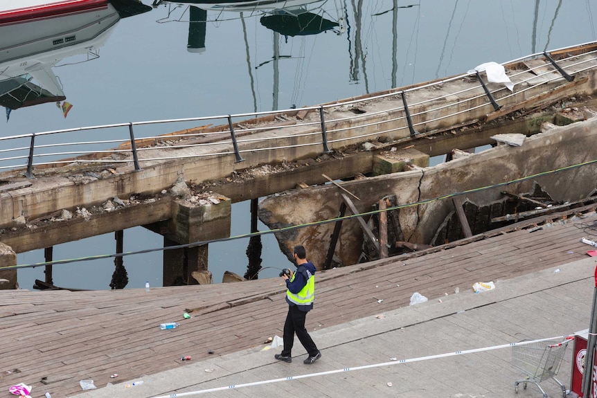 A police officer takes a photograph at the scene of a boardwalk collapse