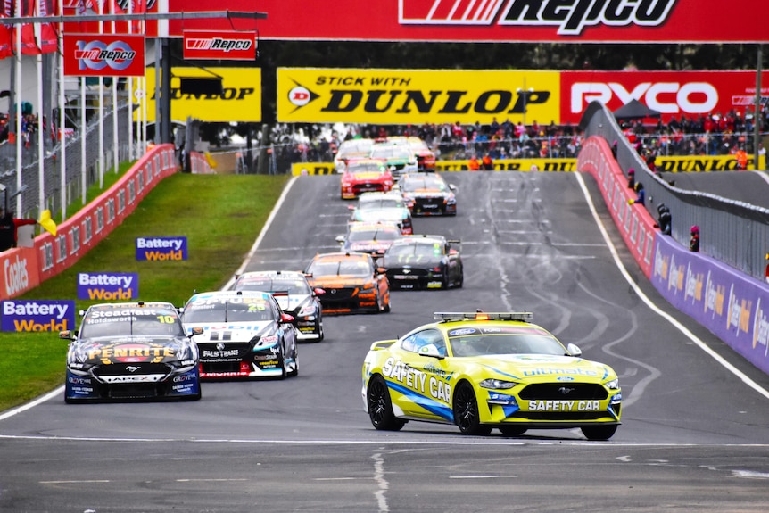A vehicle with 'safety car' written on the side turns a corner leading racecars in single file at the Bathurst 1000.