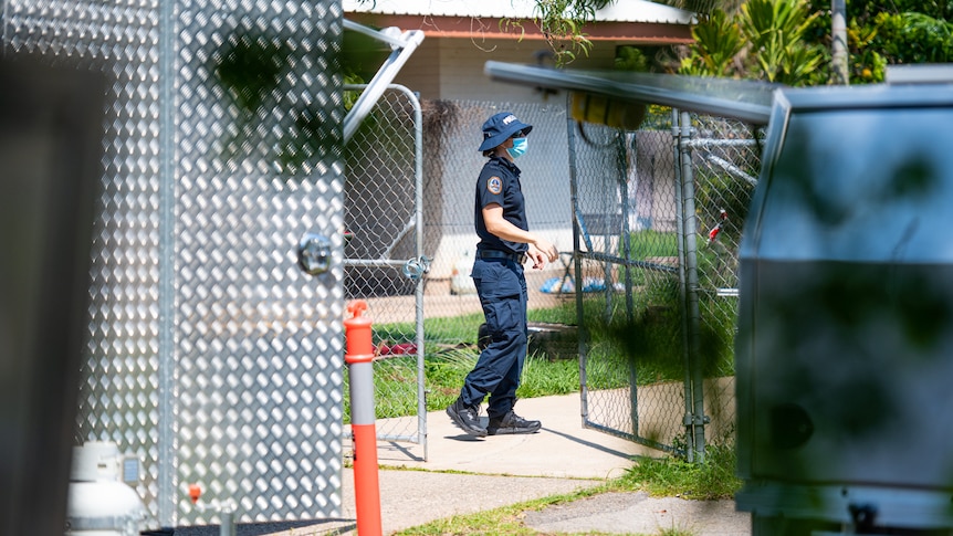 A police officer outside a home in the Darwin suburb of Malak.