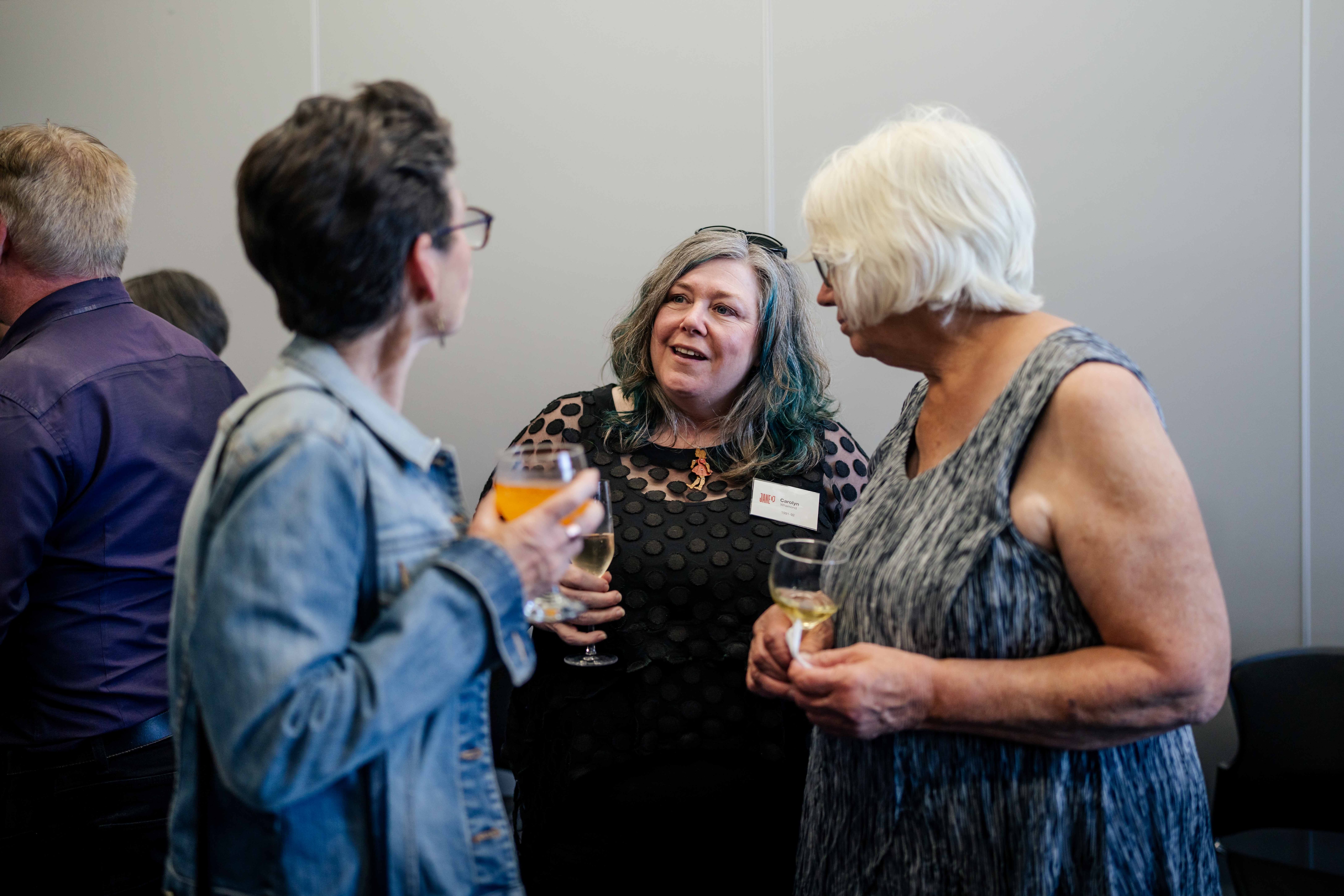 People gathered at a cocktail party, laughing, eating, drinking, chatting