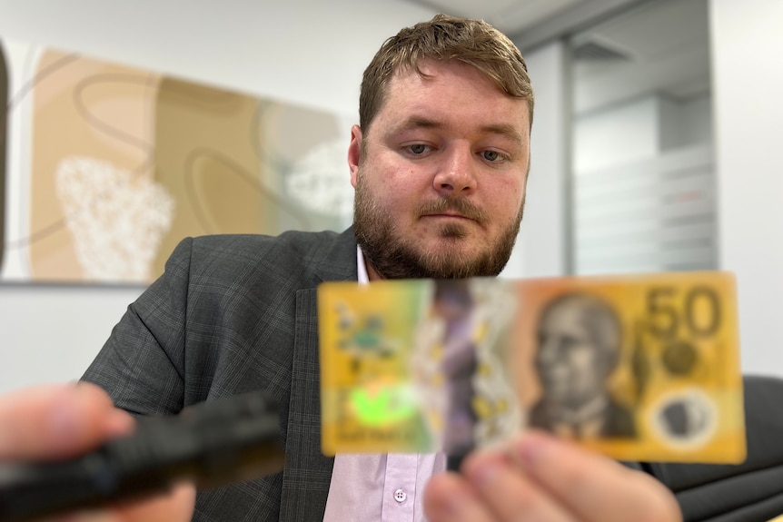 Luke Raven inspecting a banknote