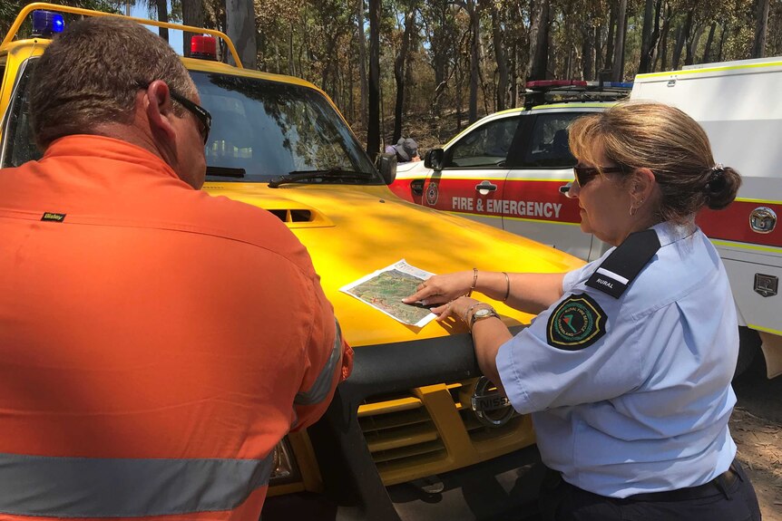 Rural Fire Service’s Tracey Charles briefing a firefighter on the bushfire burning east of Rockhampton.