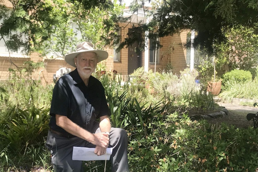 A man kneeling in the front yard of the property