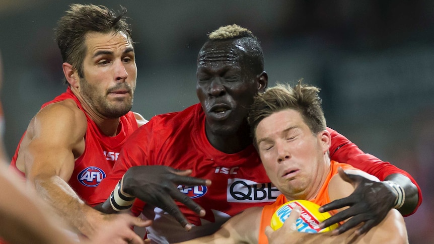 Toby Greene holds the ball with his left arm as he is tackled by Aliir Aliir and Josh Kennedy.