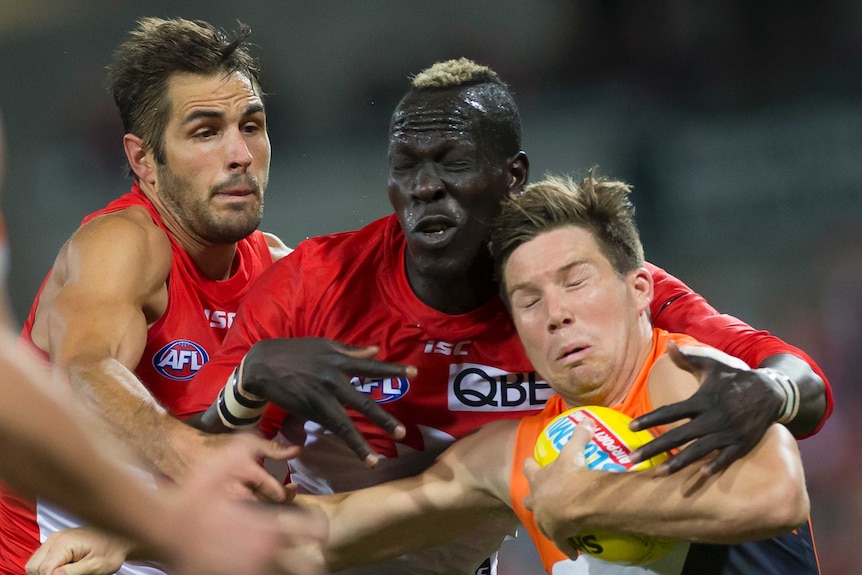 Toby Greene holds the ball with his left arm as he is tackled by Aliir Aliir and Josh Kennedy.