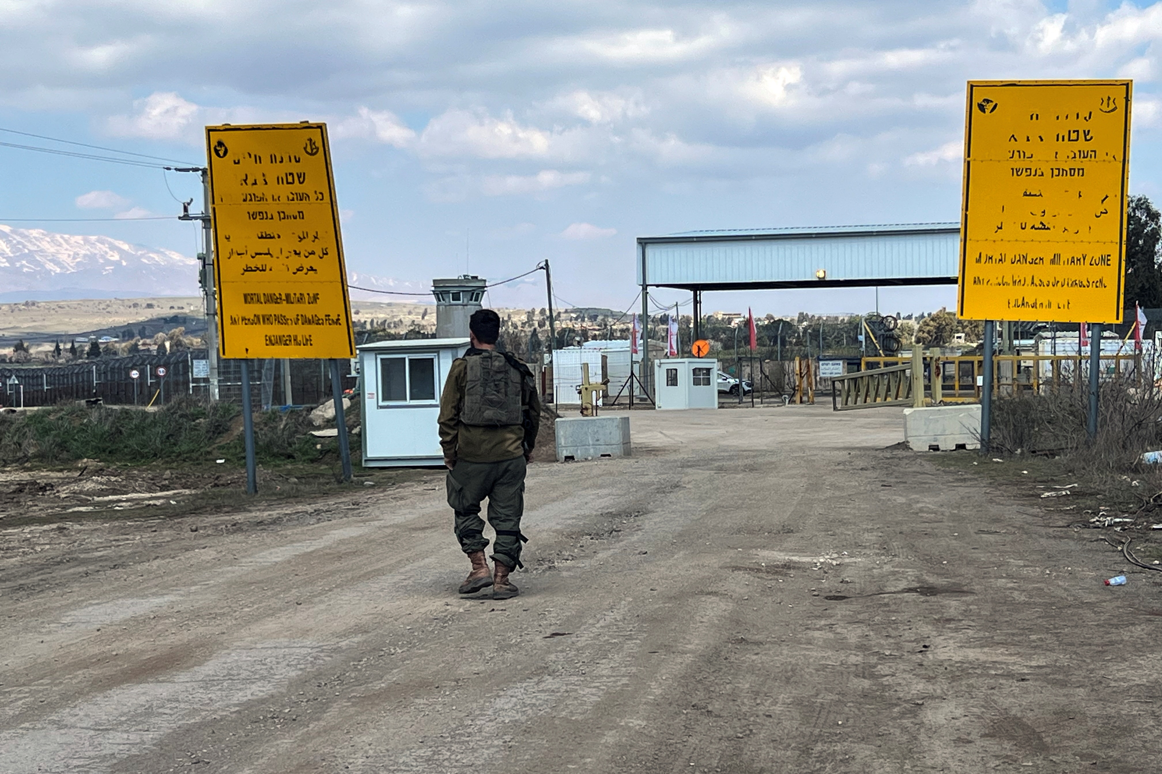 An Israeli soldier walks by the fence of the ceasefire line by Syria and the Israeli-occupied Golan Heights