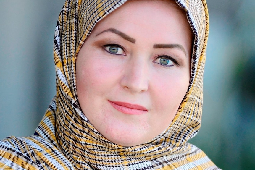 A close up portrait of Zahra wearing gold hijab and blue shirt. 