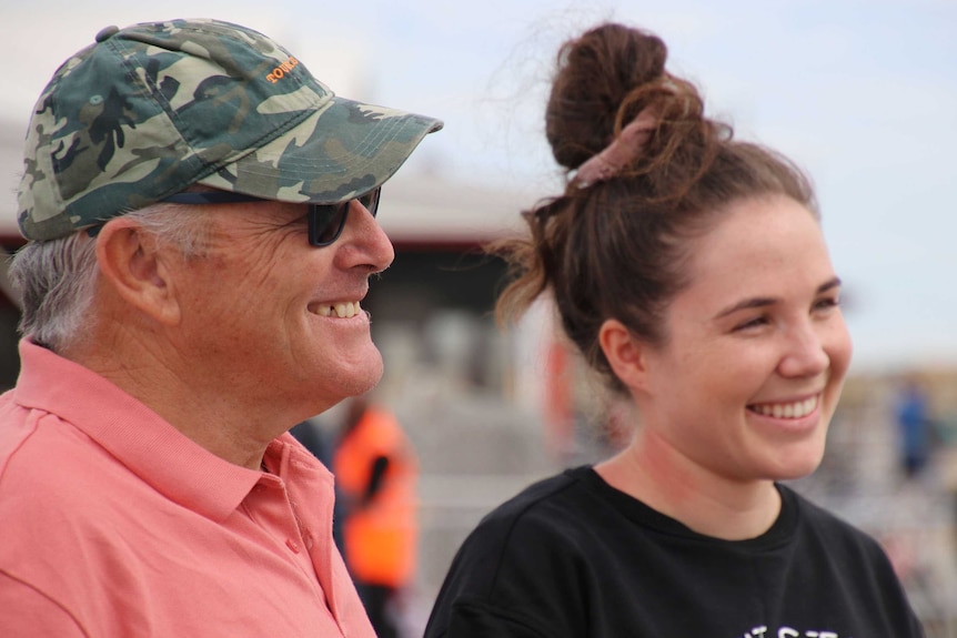 A man and daughter smile on a wharf while talking to reporters.
