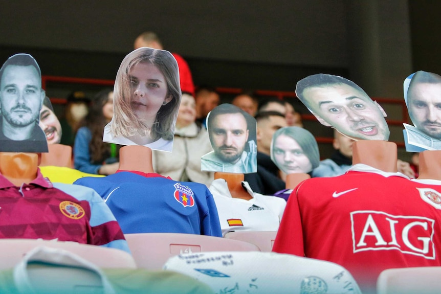 Mannequins in soccer uniforms sit with printed out faces of soccer fans attached to them.