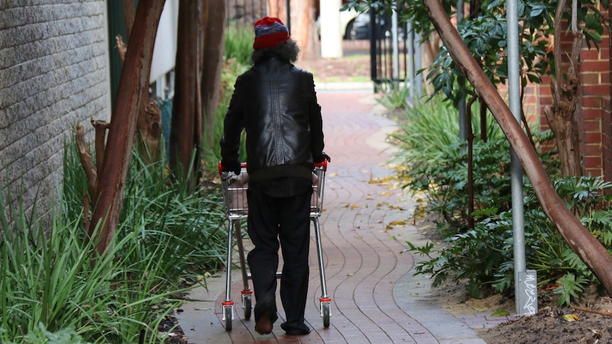 Homeless man walks through gated Perth public alley