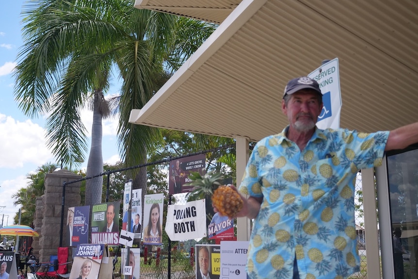 Chris 'Pineapple' Hooper outside a polling booth in Rockhampton wearing blue pineapple print shirt, holding a pineapple.