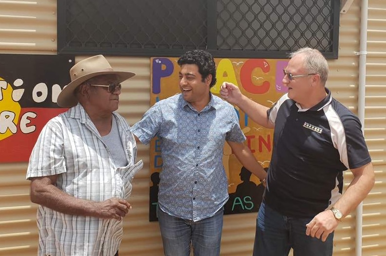 Three men stand in front of the mediation centre.