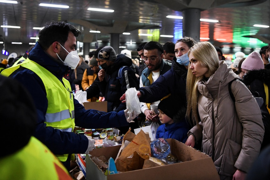 Un volontaire remet de la nourriture aux personnes fuyant l'Ukraine à la gare centrale de Berlin.