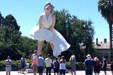 People look at a three-storey statue of Marilyn Monroe, erected in a town square.