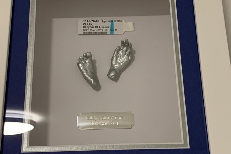 Framed sculpture of two silver baby feet