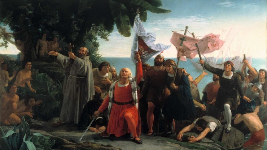 A classical painting shows a dramatic scene of Spanish colonisers carrying swords and crosses as they land on a foreign coast.