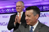 Malcolm Turnbull smiles and holds his hands together with Nevada Governor Brian Sandoval sitting in front of him.