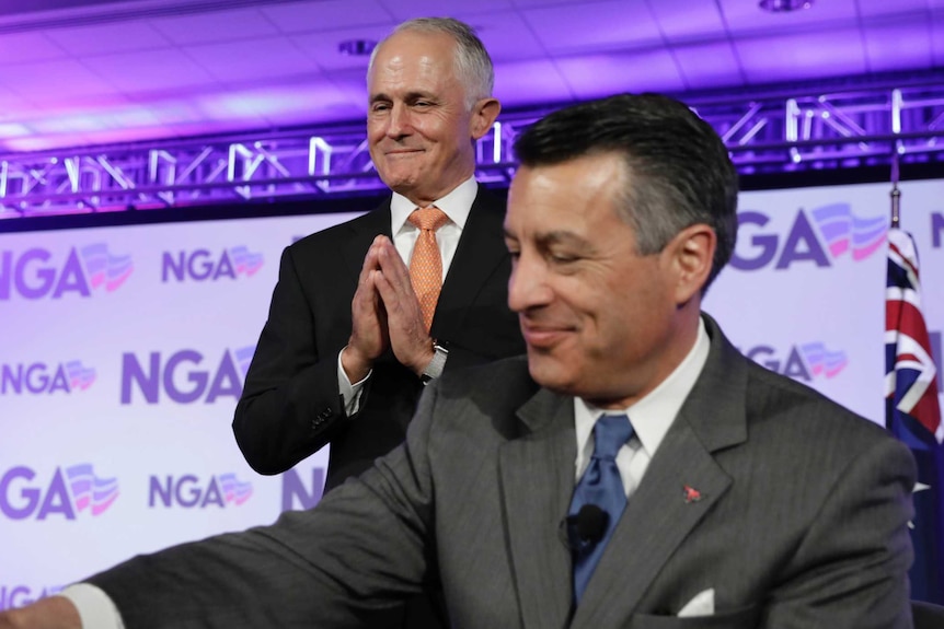 Malcolm Turnbull smiles and holds his hands together with Nevada Governor Brian Sandoval sitting in front of him.