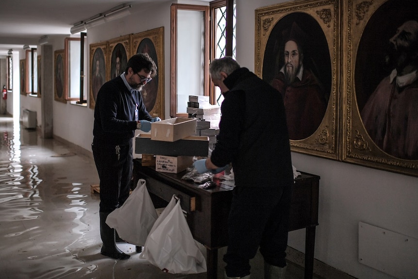 People asses damage of the church in floodwater.