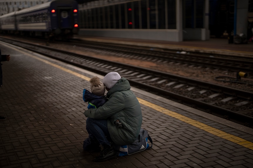 Adult and child embrace on train station platform