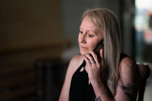 Una mujer de largo cabello rubio está hablando por teléfono. 