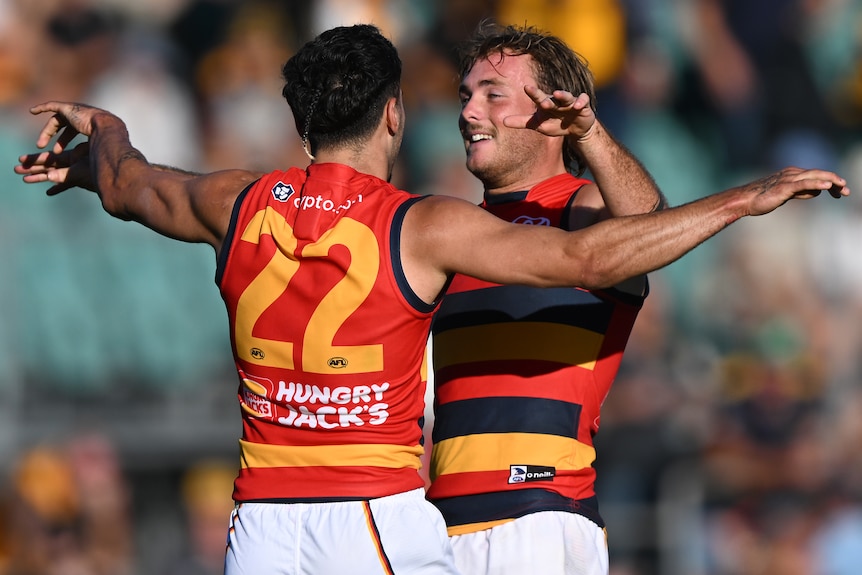 Two Adelaide Crows AFL players embrace as they celebrate beating Hawthorn.