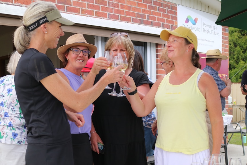 four women hold champagne glasses in a toast
