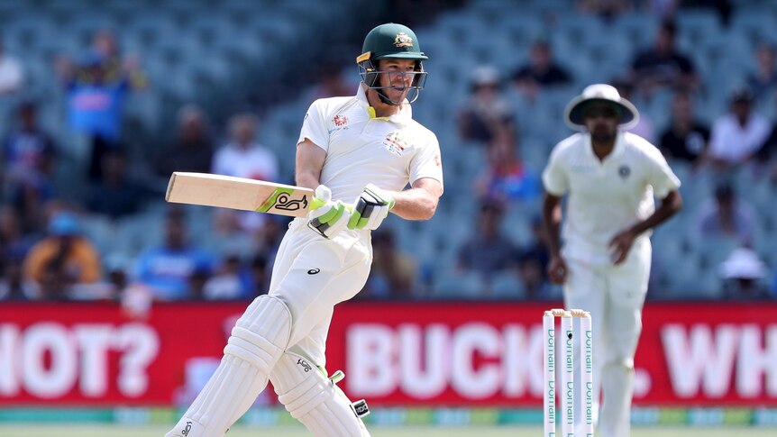 A cricket player holds his bat parallel to the ground at his hip, swivelling around on his foot