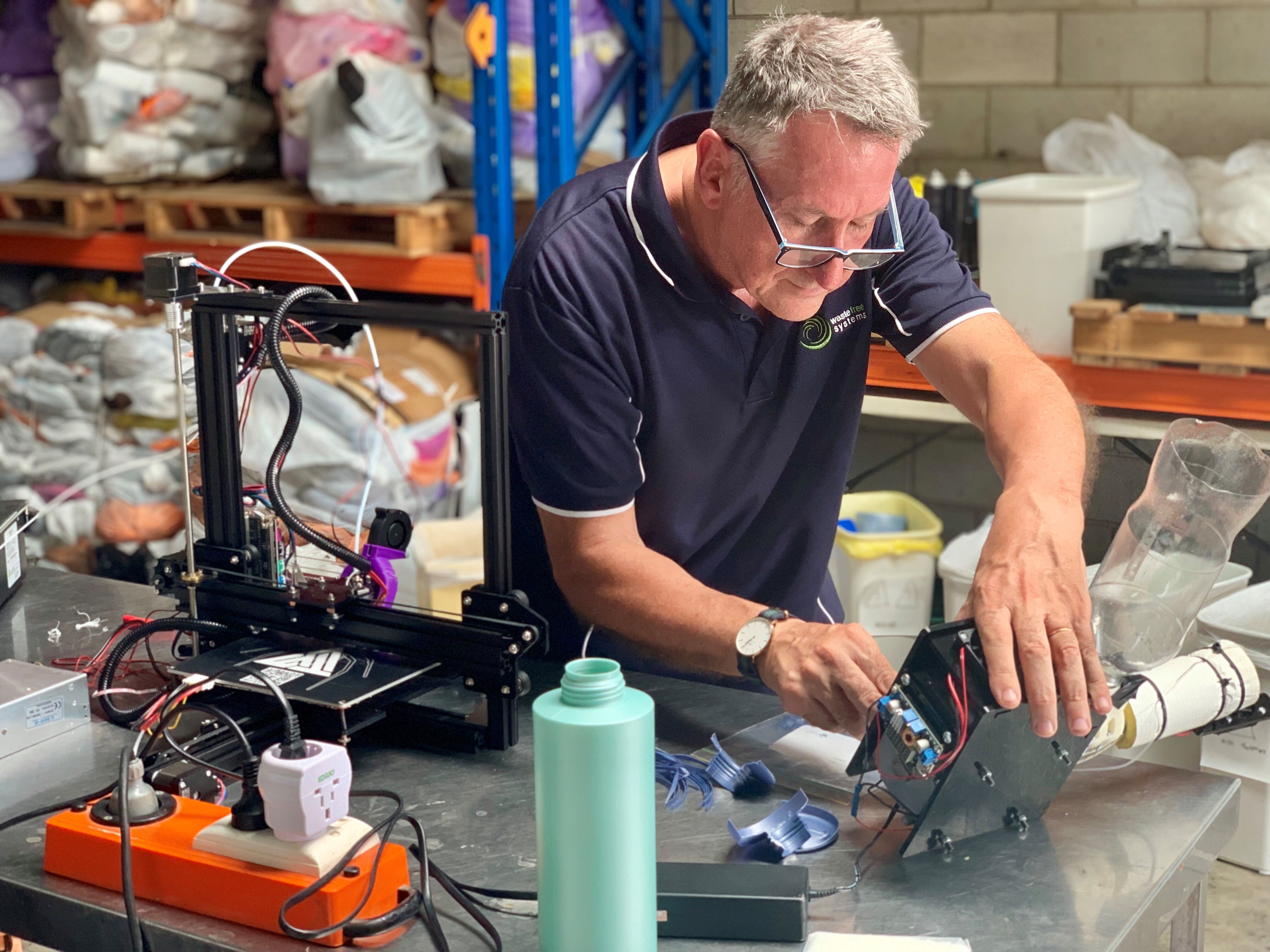 El propietario de Waste Free Systems monta la extrusora de plástico en su taller