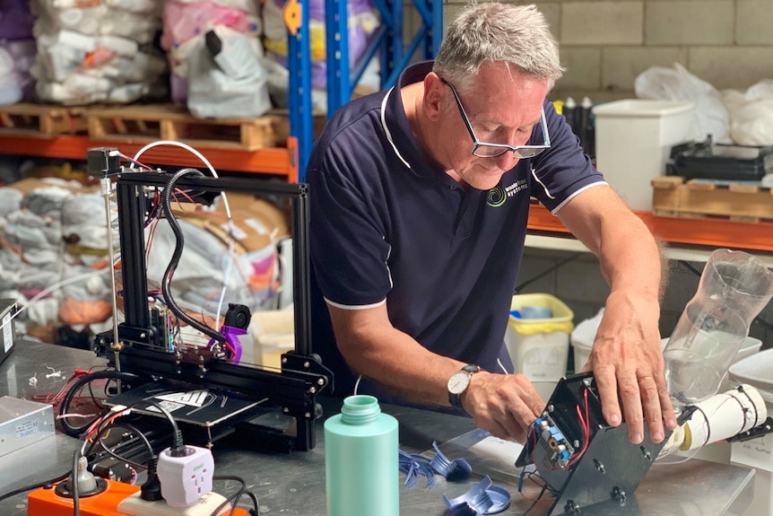 The owner of Waste Free Systems sets up the plastic extruder in his workshop