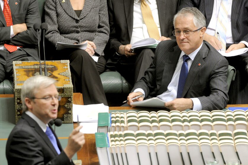 Opposition leader Malcolm Turnbull (sitting) listens to Prime Minister Kevin Rudd