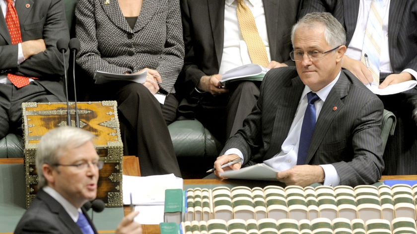 Opposition leader Malcolm Turnbull (sitting) listens to Prime Minister Kevin Rudd