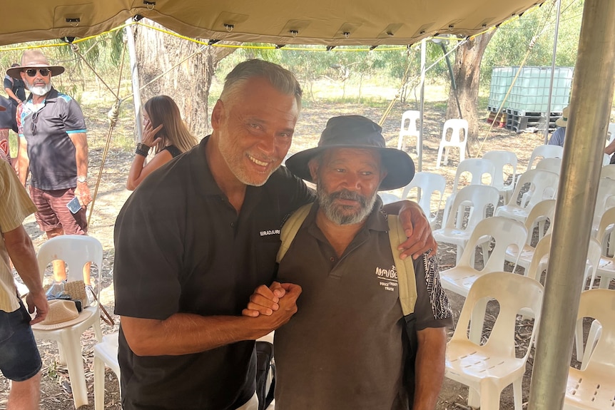 stan grant hugs an aboriginal man wearing a hat