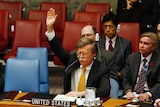 An image from 2006 of John Bolton sitting as his desk raising his hand to vote at the UN Headquarters