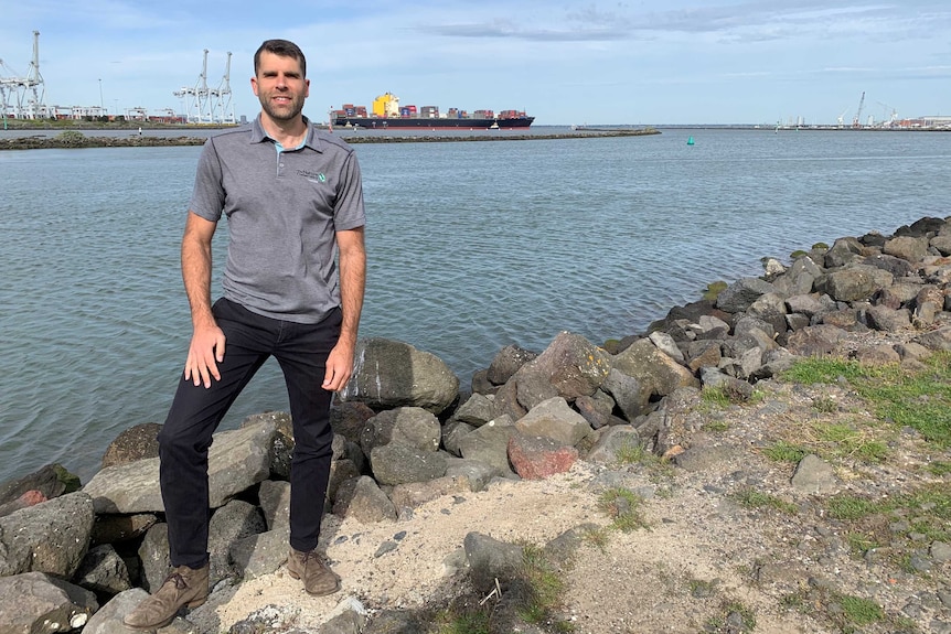 Dr Chris Gilles stands near a bay with port infrastructure in the background.