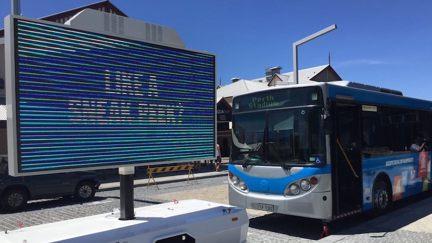 A government advertising bus pictured next to a sign reading "Like a sneak peek?".