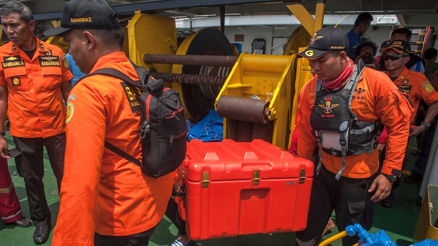 Rescuers carry a box containing the flight data recorder from the crashed Lion Air jet.