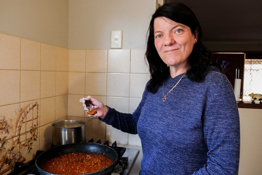 A close up of a saucepan with spaghetti sauce being stirred