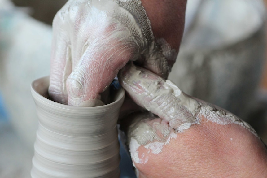 A close-up of some hands covered in clay.