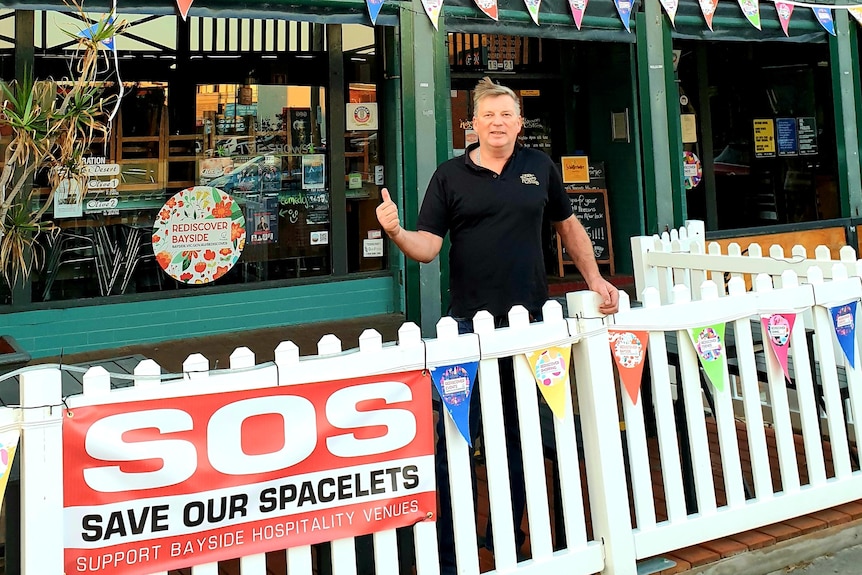 Man stands outside his pub where he has an outdoor dining area.