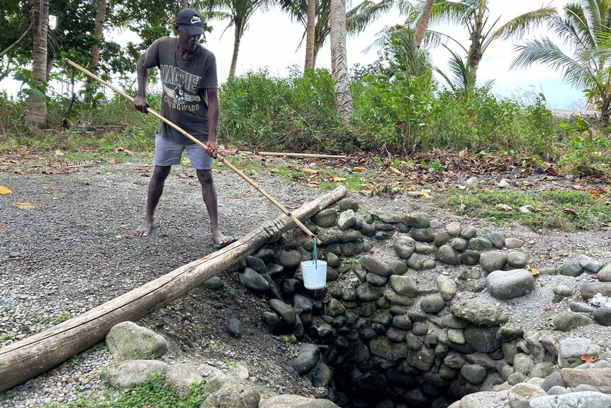Victor Peter Kere from Savo Island reaching into a traditionally constructed water well