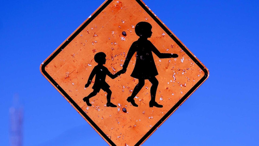 A school crossing sign which is slightly bent out of shape.