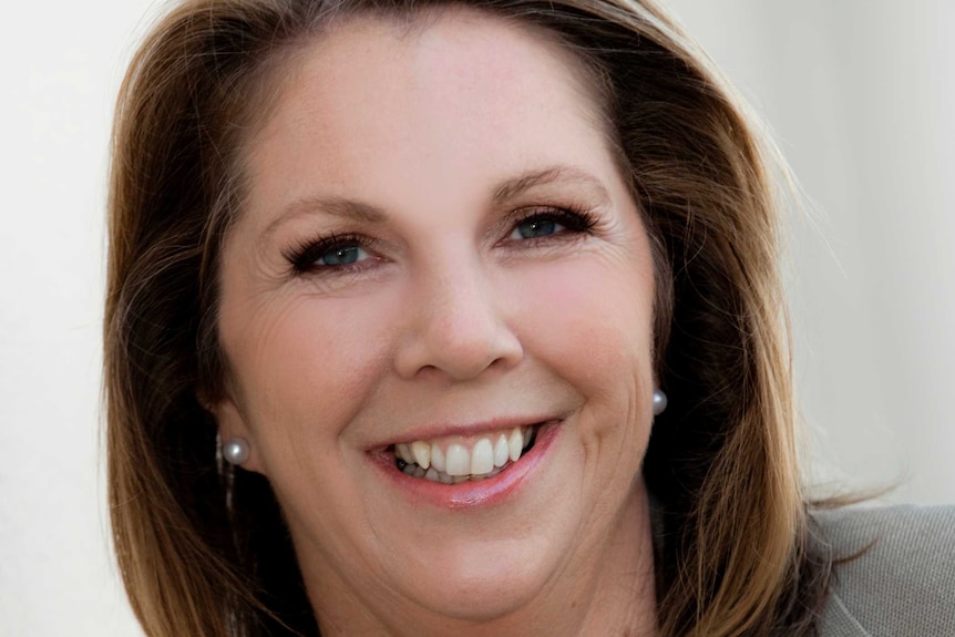 A dark-haired woman, formally dressed, smiling for a professional headshot.