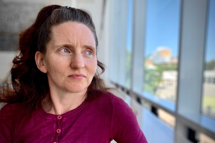 Woman looks out the window of an office building.