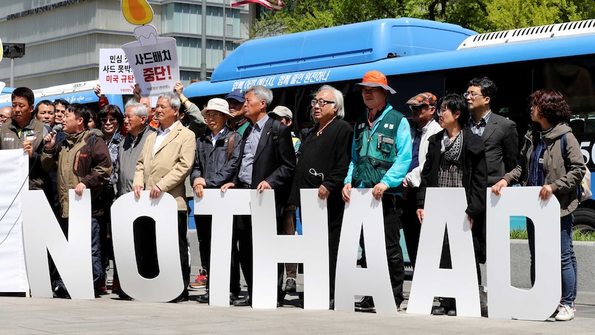 Protesters hold letters reading "No THAAD".