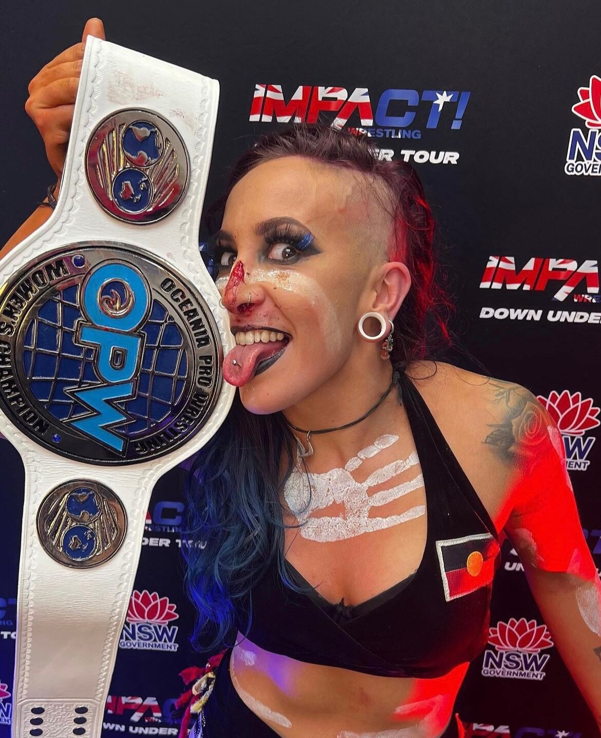 female wrestler holding a championship belt to her face.