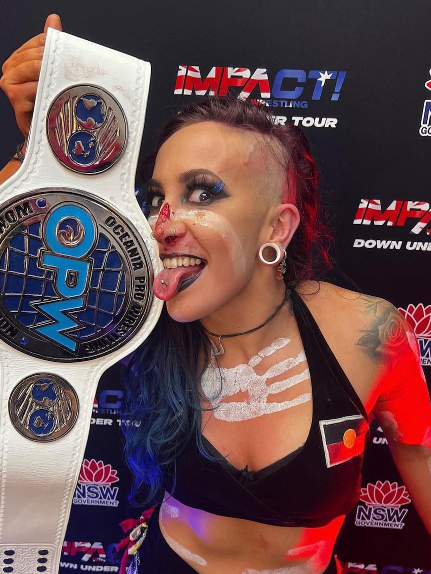 female wrestler holding a championship belt to her face.