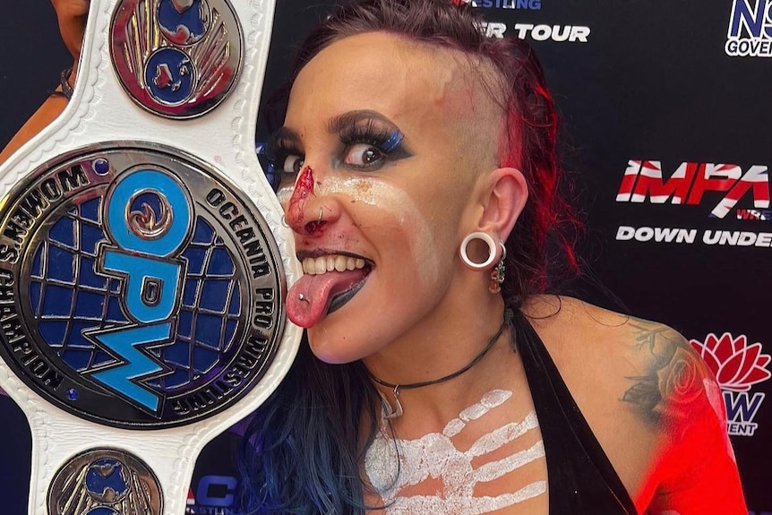 female wrestler holding a championship belt to her face.