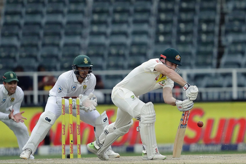 Shaun Marsh blocks the ball while Quinton de Kock watches on from behind the stumps.